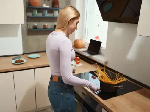Donna cucina la pasta su piano cottura autoalimentato