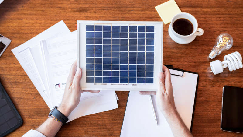 uomo-con-un-campione-di-pannelli-solari uomo che osserva un campione di pannello fotovoltaico e si occupa della burocrazia